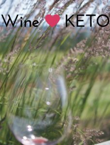 a wine glass over a green field- can you have wine on the keto diet?