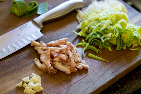 Sliced leeks, bacon and garlic on a cutting board