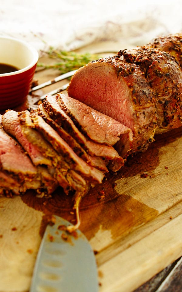 sliced roast beef with a roast beef rub on a cutting board