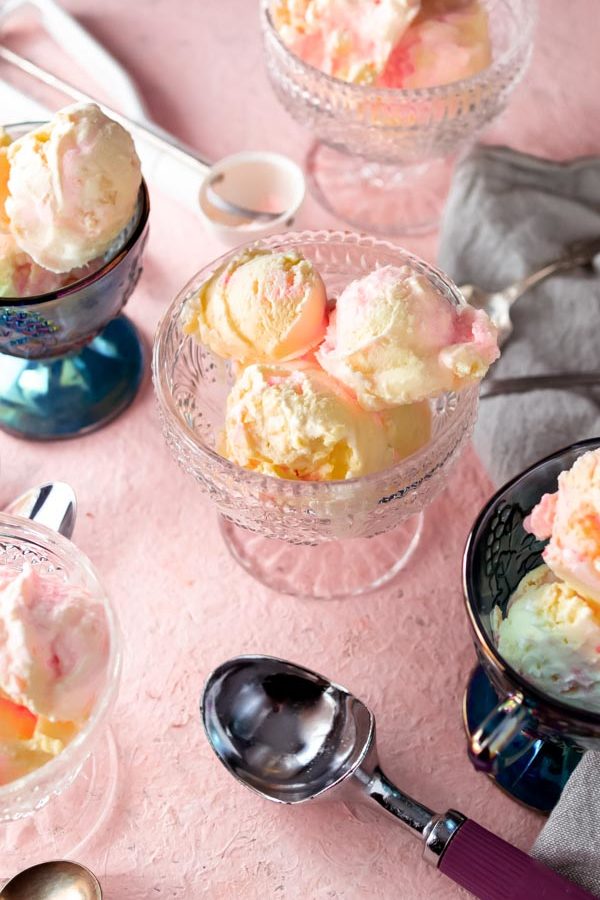 Peppermint keto ice cream scooped into dishes with spoons and a pink background